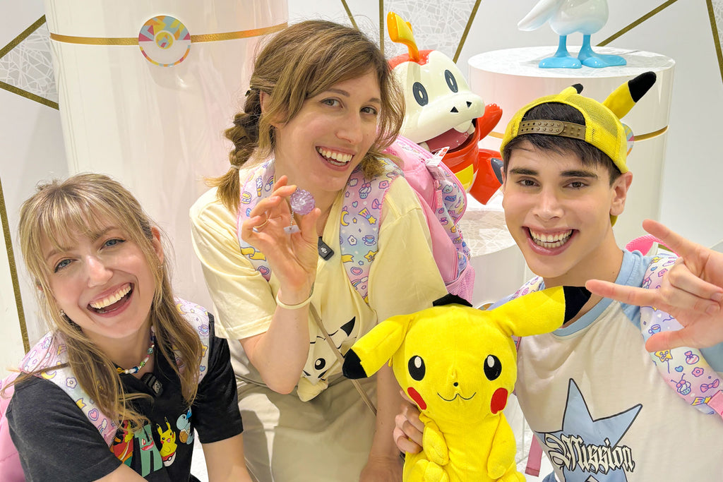 Three people posing with Pikachu plush toys in Tokyo Pokemon Cafe.
